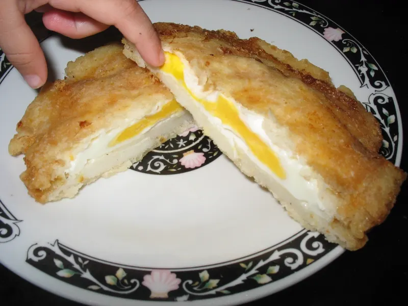 Arepa de huevo, con el huevo cocinándose dentro de la masa frita